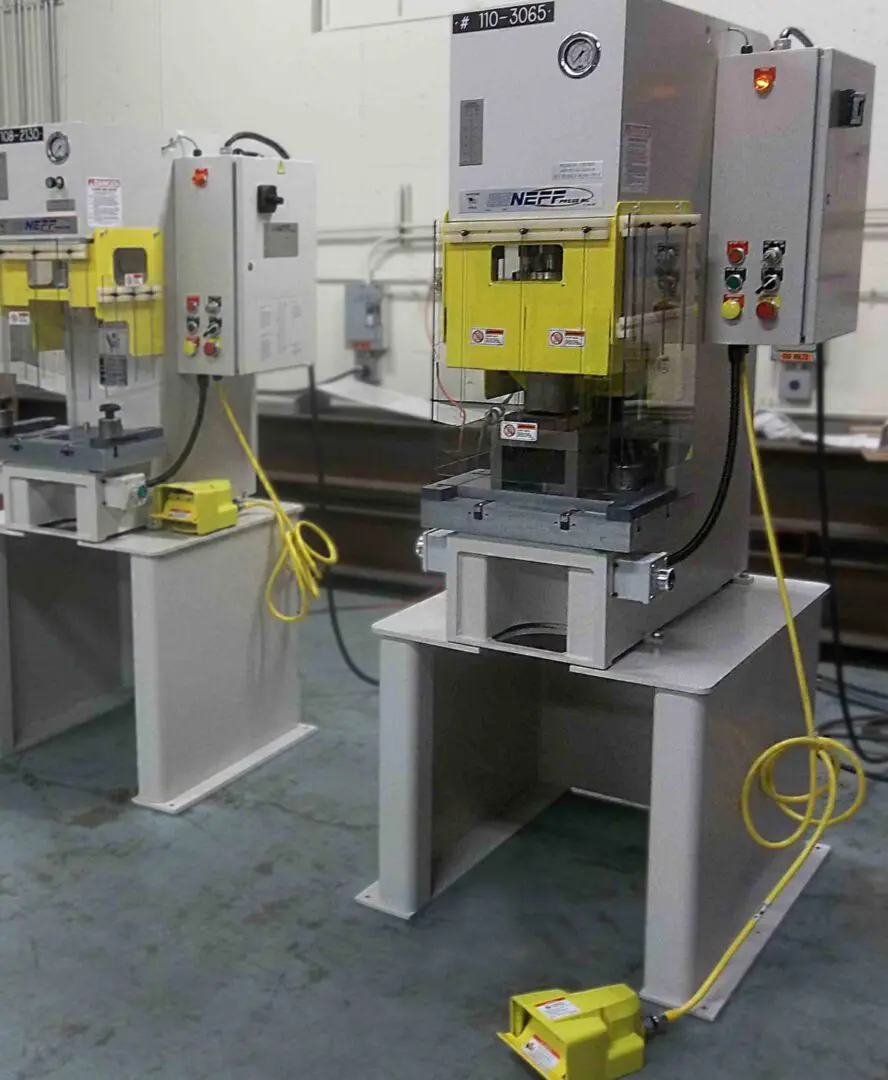 A row of machines in a room with tables.