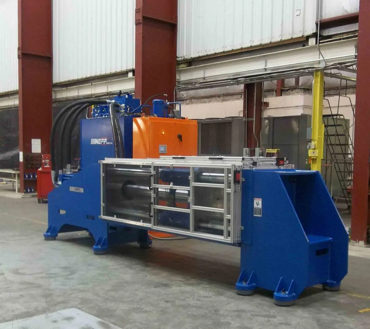 Metal-Impact-1200x1067 A large machine in a warehouse with a blue body.
