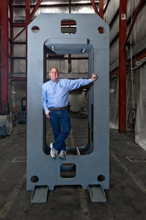John Murphy of Neff Press standing inside a large custom hydraulic press frame at the company's manufacturing facility